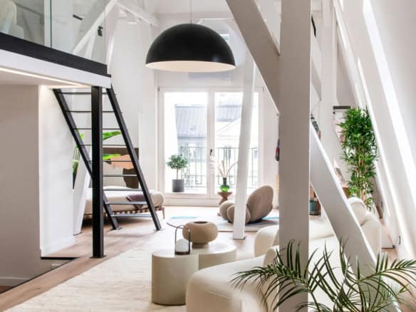 Modern lakásbelső loft stílusban, fehér színű fából készült szerkezeti elemekkel, nagy ablakokkal, minimalistikus kialakítással és belső növényekkel, világos padlóval.